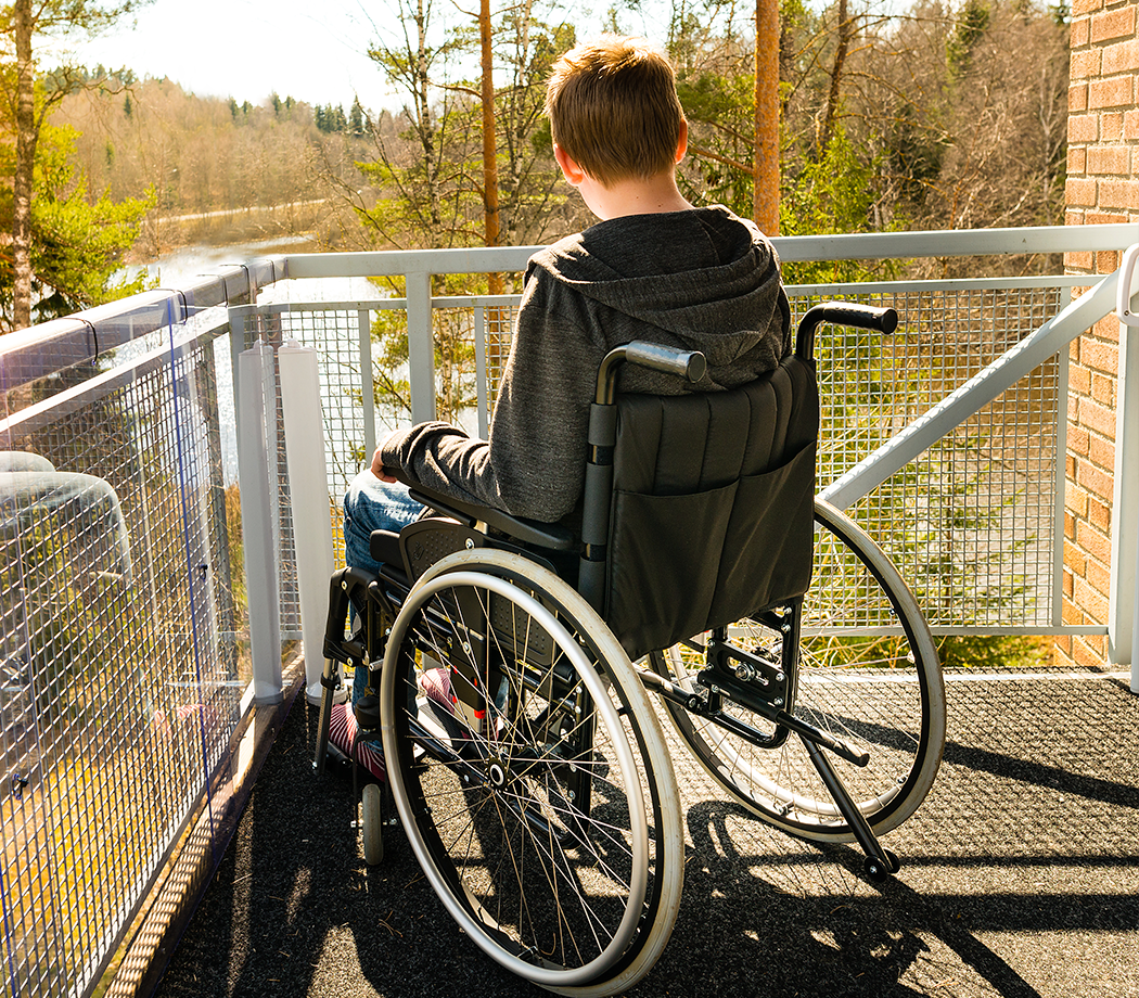 Photo of a child wheelchair user looking out off of a deck.