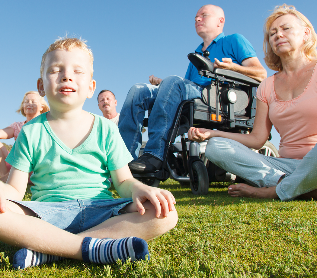 Adaptive Yoga, man in power wheelchair practicing yoga with his family outside