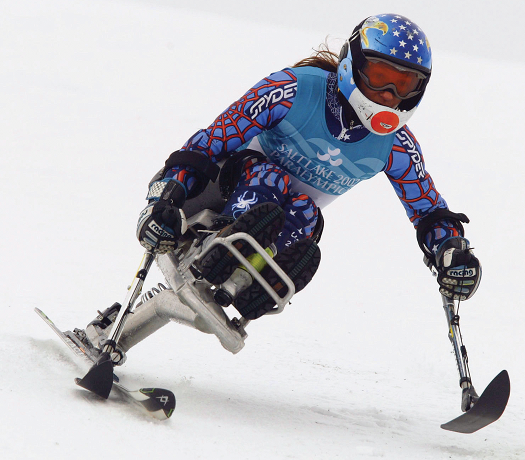 Disabled woman mono skiing down a snow covered hill.