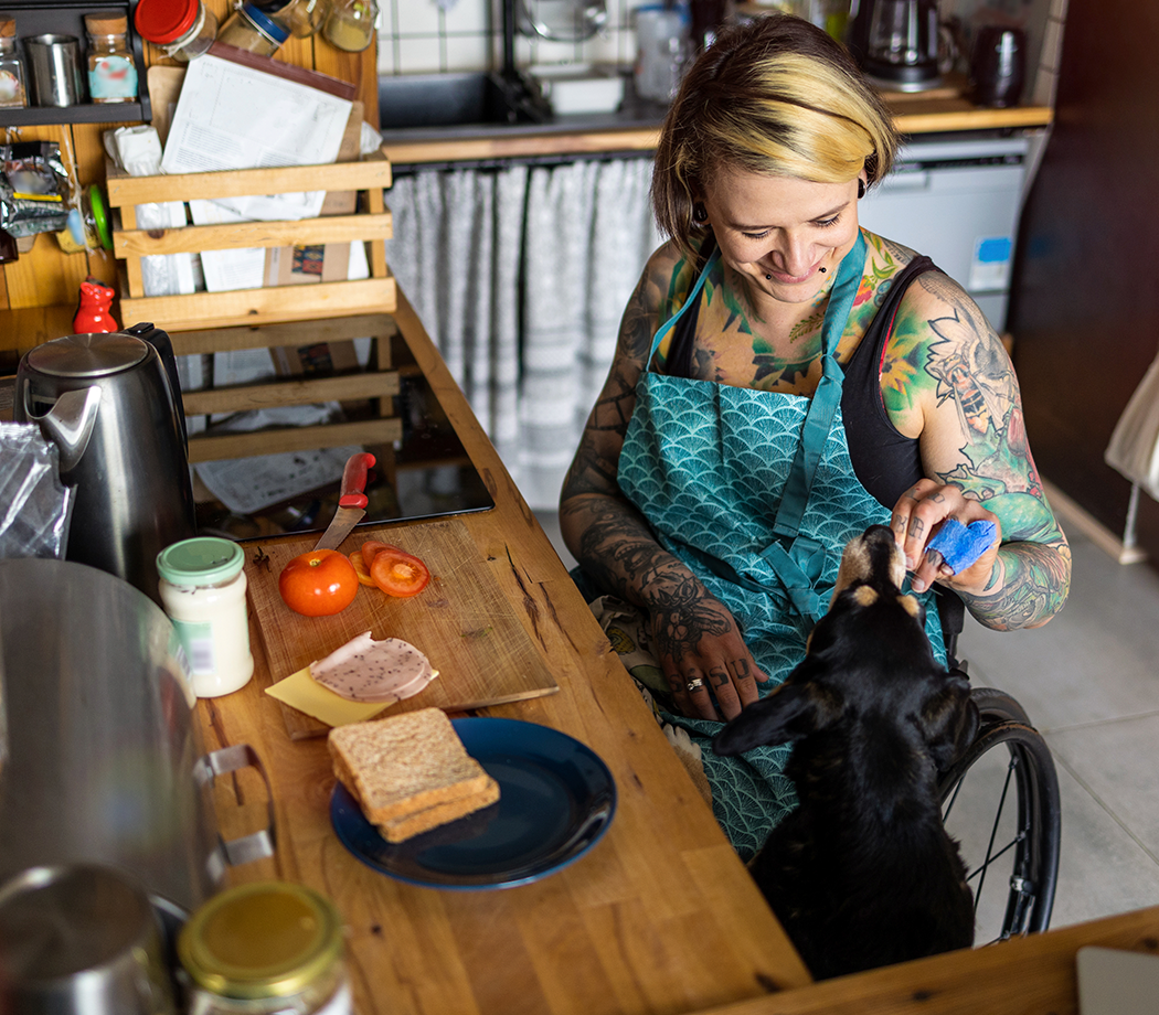 Woman in wheelchair preparing food in kitchen at home