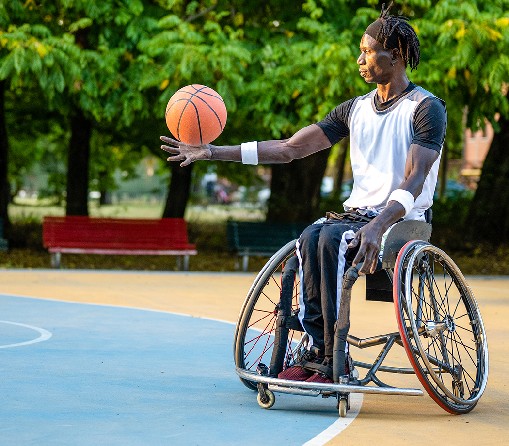 Basketball athlete on a wheelchair, African American male with disabilities playing sport outdoors