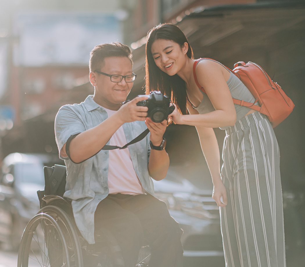 Woman with man in a wheelchair holding a camera