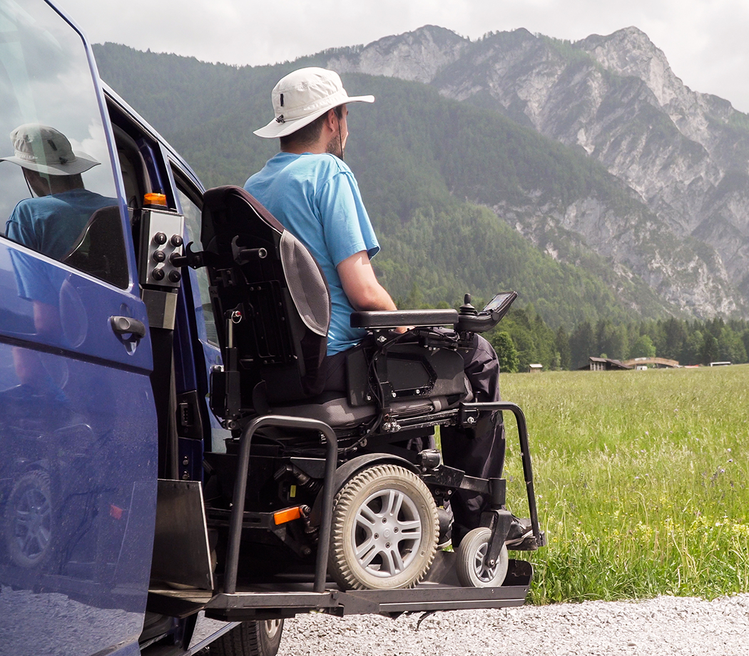 Electric lift specialized vehicle for people with disabilities. Empty wheelchair on a ramp with nature and mountains in the back