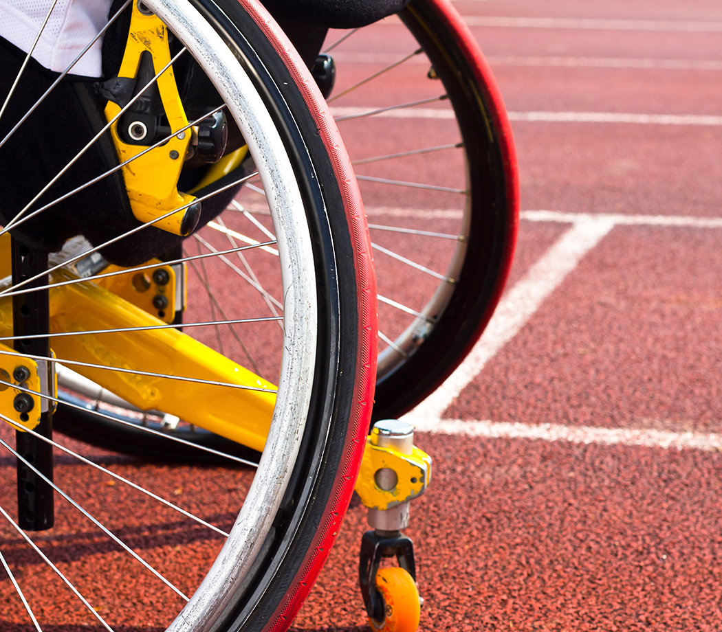 Close up of a wheelchair wheel on a track.