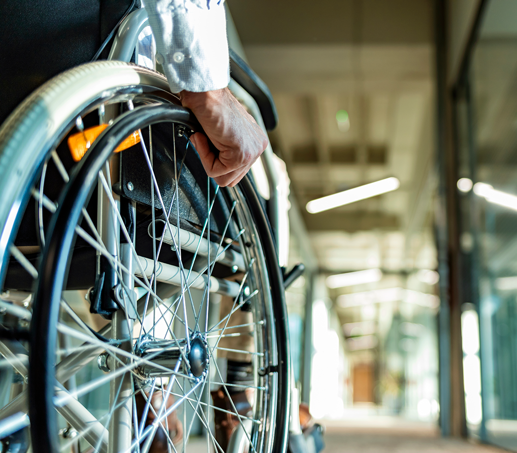 Man in a wheelchair rolling down a work hallway